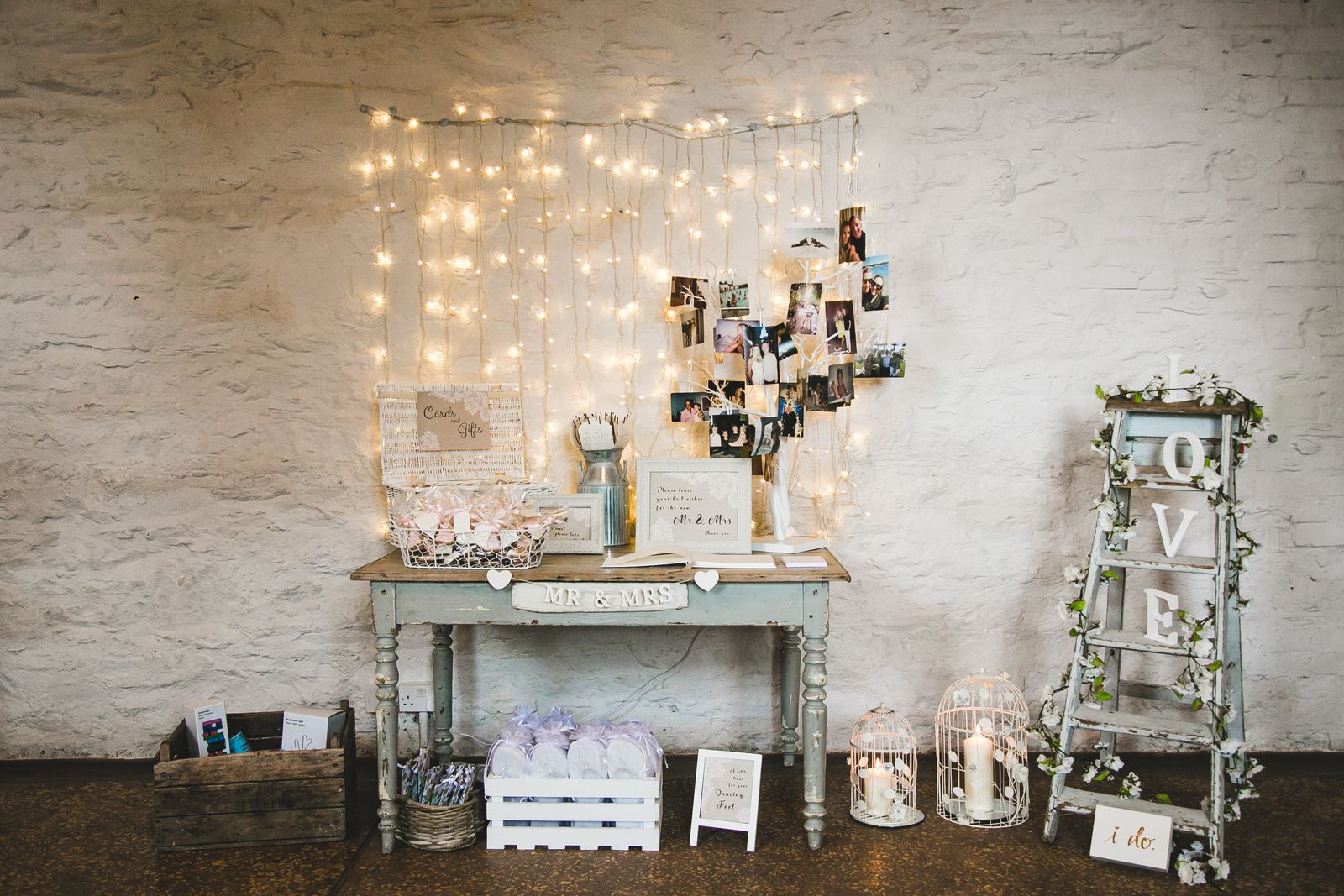 Cards table and glowing fairy lights in front of a rustic barn wall.